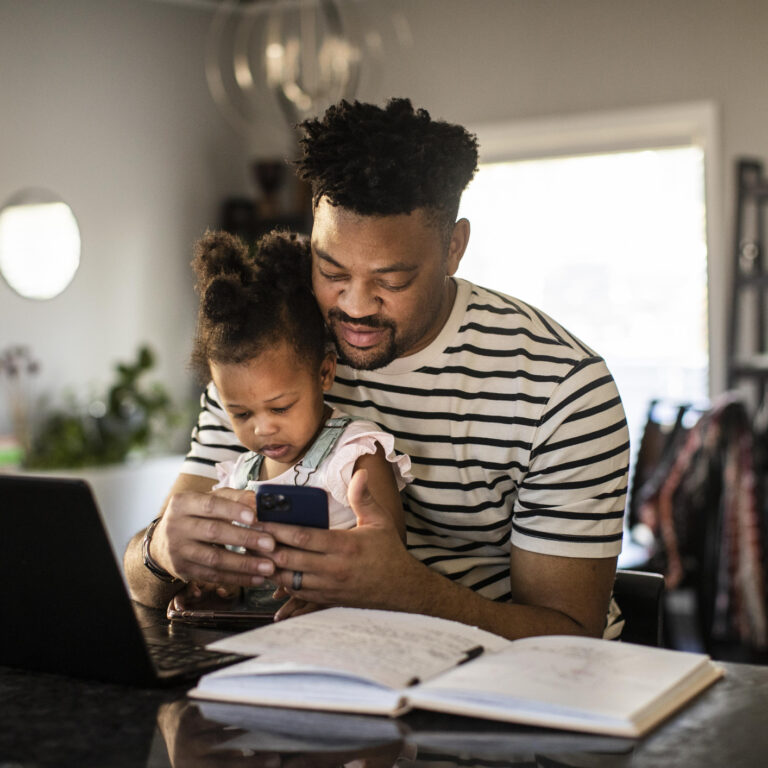 Father working from home while holding toddler